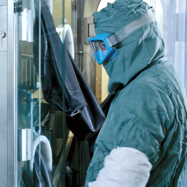 Gowned worker in manufacturing area for cytotoxic products